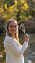 Portrait of young woman with arms raised standing in lake