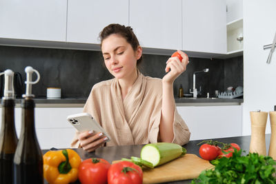 Portrait of young woman holding apple while sitting at home