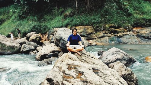 Portrait of young woman sitting on rock