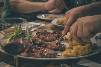 Cropped hands eating food on dining table