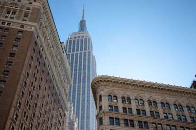 Low angle view of empire state building at flatiron building against clear sky