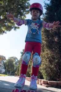 Full length of happy girl standing against trees