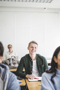 Smiling young man sitting at desk in classroom