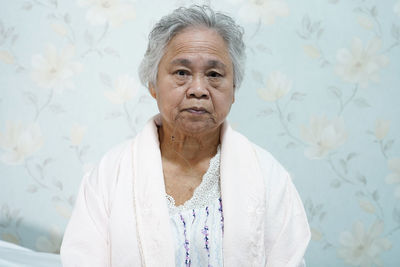 Portrait of senior woman standing against wall