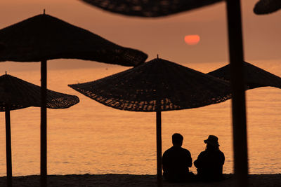 Rear view of silhouette people at beach during sunset