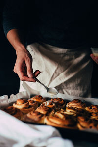 Midsection of person making cinnamon buns in tray