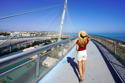 Woman walking on pescara modern bridge enjoying seascape from promenade in abruzzo region, italy