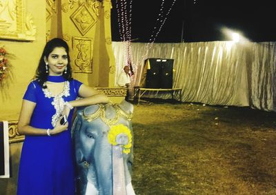 Portrait of smiling young woman standing against wall