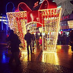 People walking on illuminated street at night