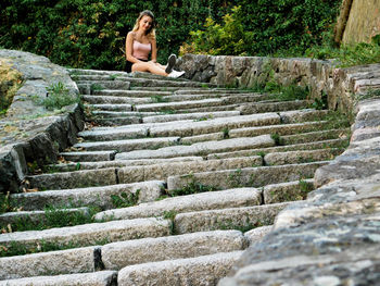 Low angle view of young woman sitting on steps