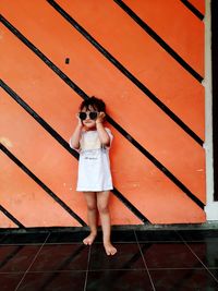 Full length of woman standing against wall