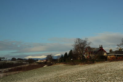 Houses on field by buildings against sky