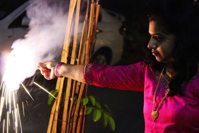 Mid adult woman playing with sparklers at night