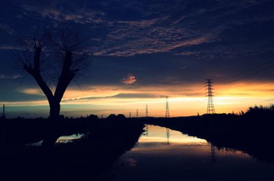 Reflection of trees in sea at sunset