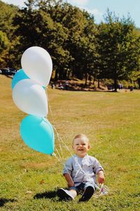 Full length of boy with balloons on field
