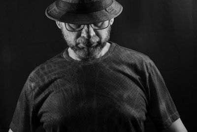 Black and white portrait of a man wearing a hat and glasses. isolated on black background.