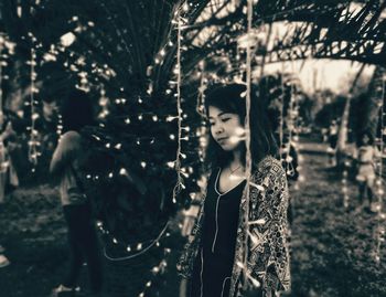 Young woman standing by tree