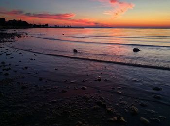 Scenic view of sea against dramatic sky during sunset