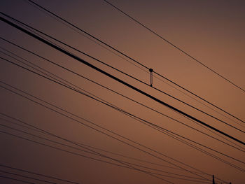 Low angle view of power cables against sky during sunset