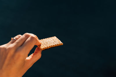 Cropped hand of person holding gift box against black background