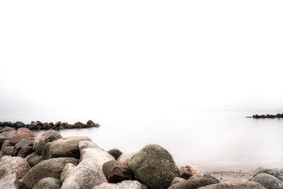 Rocks in sea against clear sky