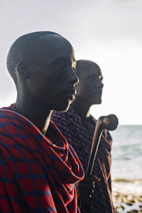 Two masai men in traditional clothes standing in front of sea