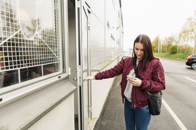 Young woman using mobile phone while entering industry