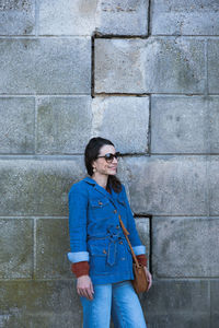 Full length of woman standing against brick wall