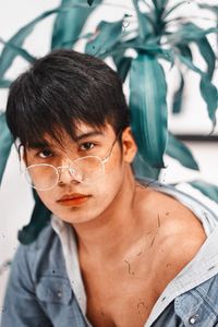 Close-up portrait of young man wearing eyeglasses against plants