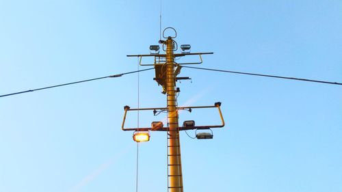 Low angle view of telephone pole against clear blue sky