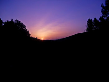 Silhouette landscape against clear sky at sunset