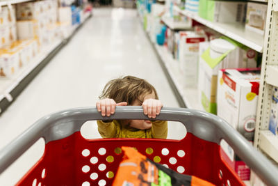 High angle view of girl holding shopping cart while standing in supermarket