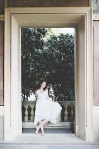 Beautiful smiling curly hair brunette in a light blue simple dress in a pavilion in a garden