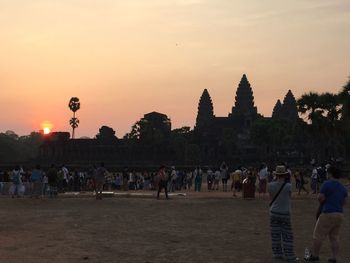 People at temple against sky during sunset