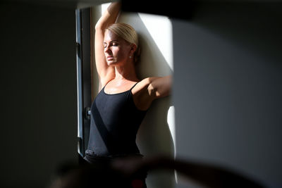 Woman with eyes closed standing by wall