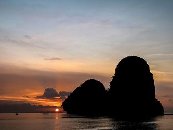 Silhouette rocks by sea against sky during sunset