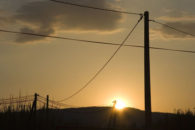 Silhouette electricity pylon against sky during sunset