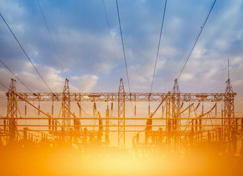 Low angle view of cranes against sky during sunset