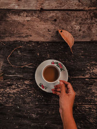 Cropped hand holding coffee on table