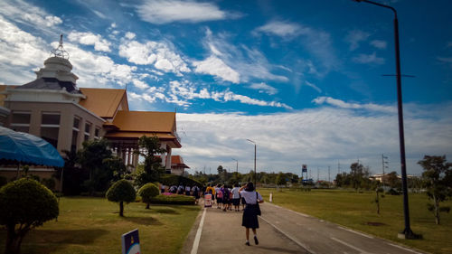 People on road by buildings against sky