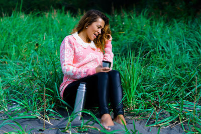 Young woman using mobile phone while sitting on grass
