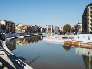 Reflection of buildings in canal against clear sky