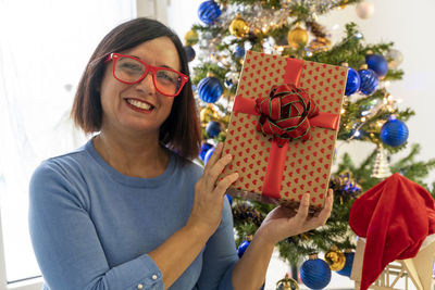 Portrait of woman wearing sunglasses while sitting on sofa at home