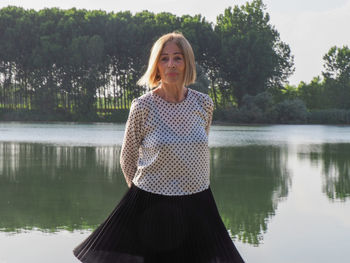 Portrait of young woman standing against lake