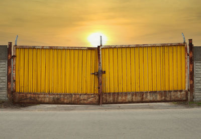 Yellow metal gate against sky during sunset