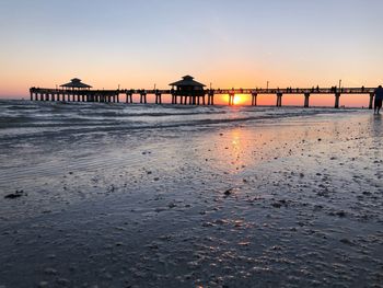 Pier over sea against sky during sunset