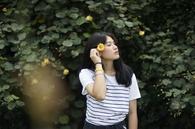 Woman wearing flowers standing against plants in park