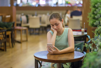 Portrait of teenage girl sitting on chair at home