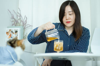 Woman in pajamas cloth drink tea and play with her cat