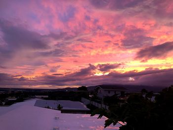 Houses and buildings against dramatic sky during sunset